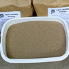 Container of mealworm frass with packaging in the background