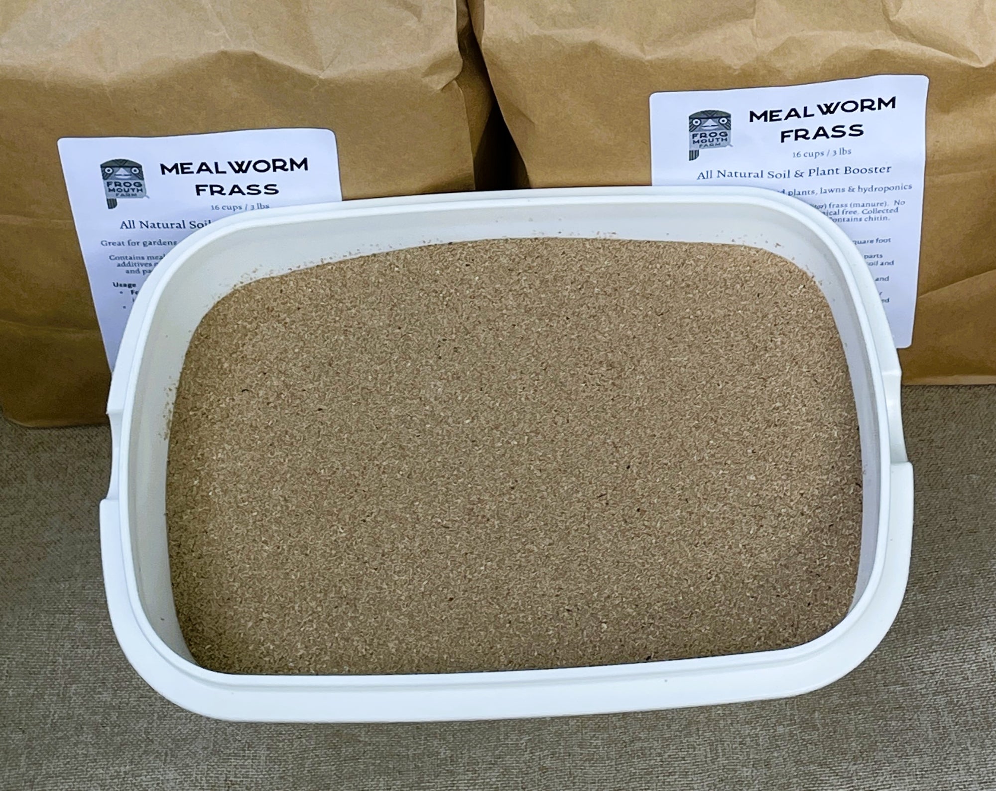 Container of mealworm frass with packaging in the background